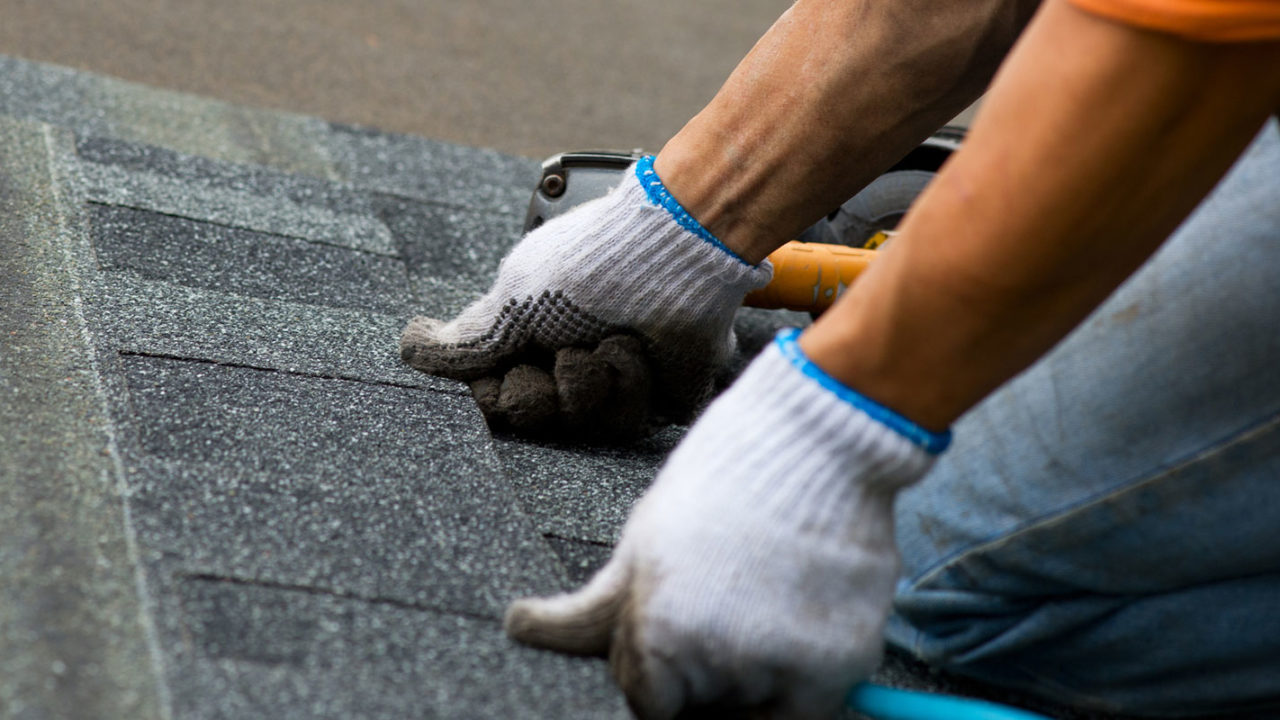 Roofing Contractor placing roofing on by hand