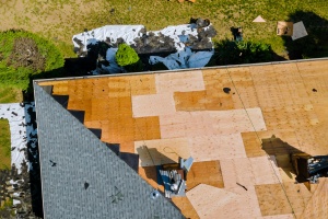 A roofer nailing shingles with air gun to replace roof before selling home