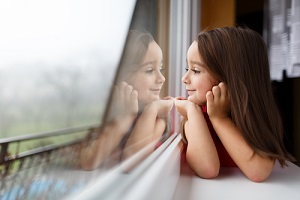 little girl smiling and watching out the window