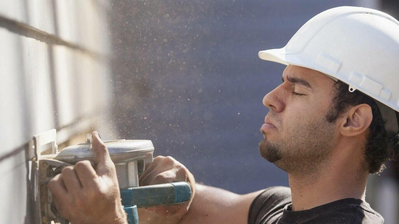 carpenter trimming house siding during renovations to add a deck