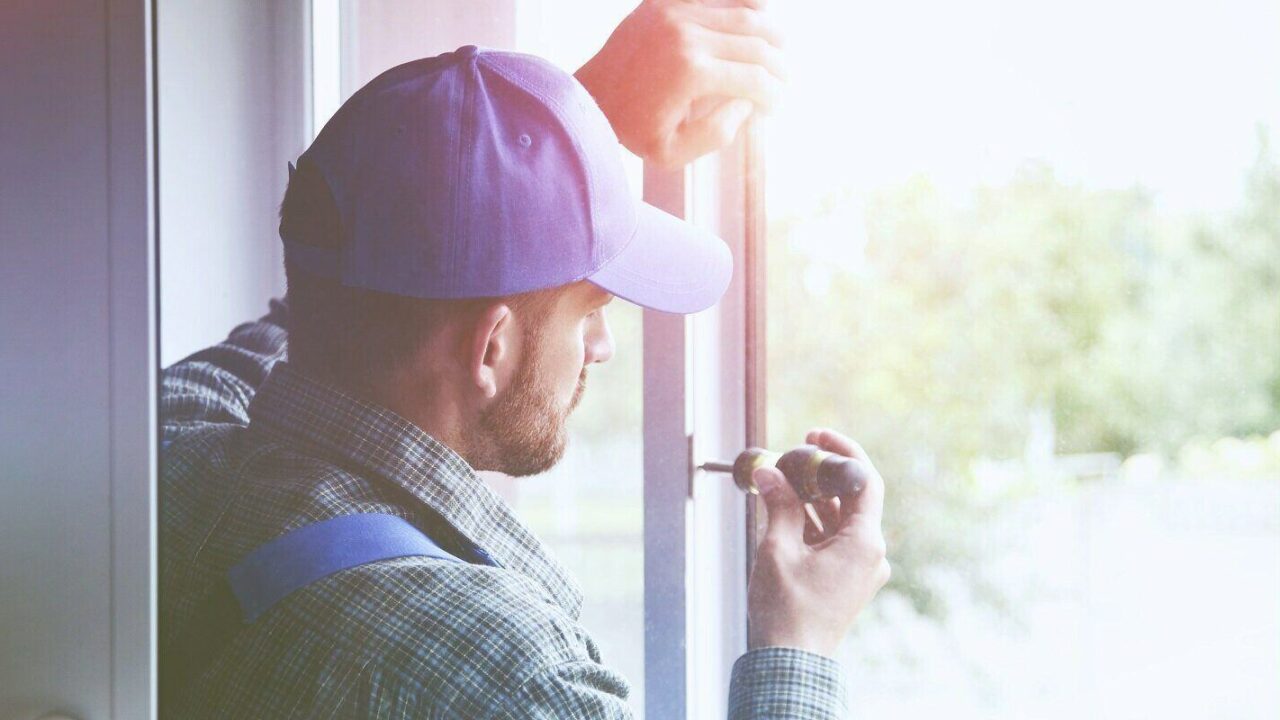 service man installing window with screwdriver