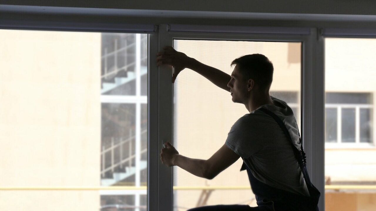 construction worker installing window in house