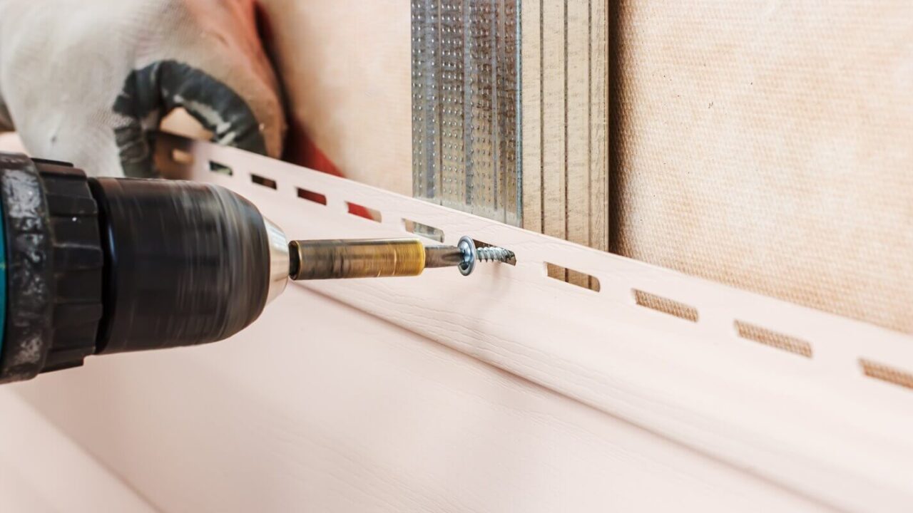 man screws in a wall using an electric screwdriver