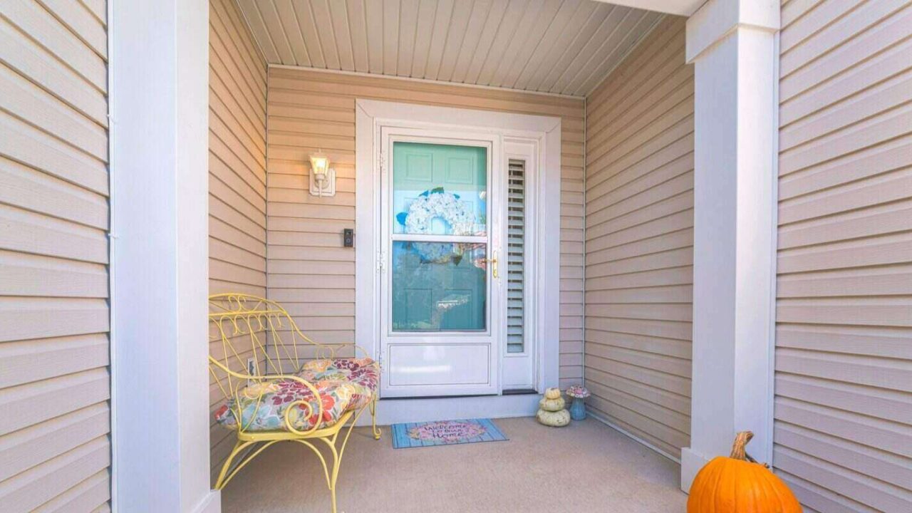 beige vinyl lap siding and glass storm door over the wreath on the front door