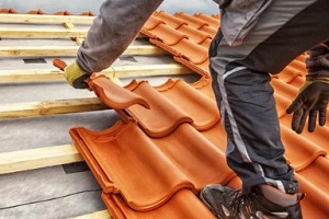 man installing clay tile on the roof