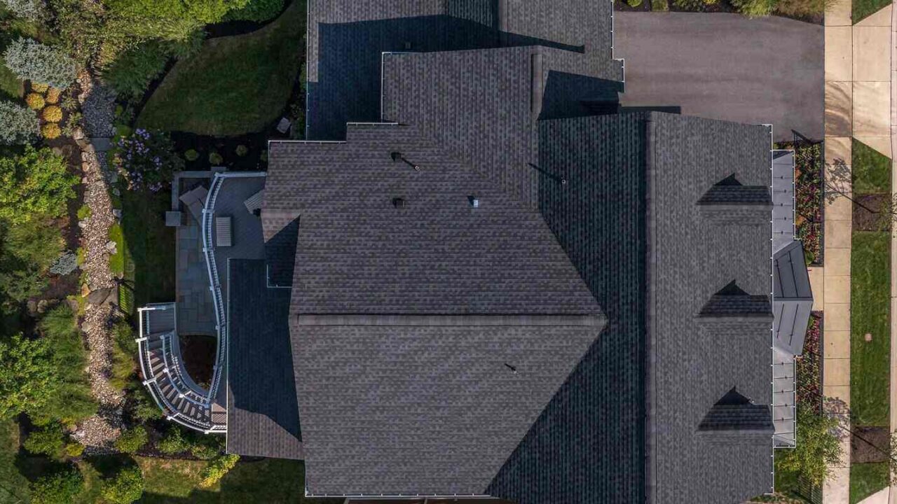 top down view of a complex hip and valley pitched roof with three dormers on a new construction American luxury single family house